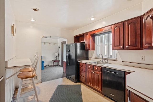 kitchen featuring visible vents, black appliances, a sink, arched walkways, and light countertops