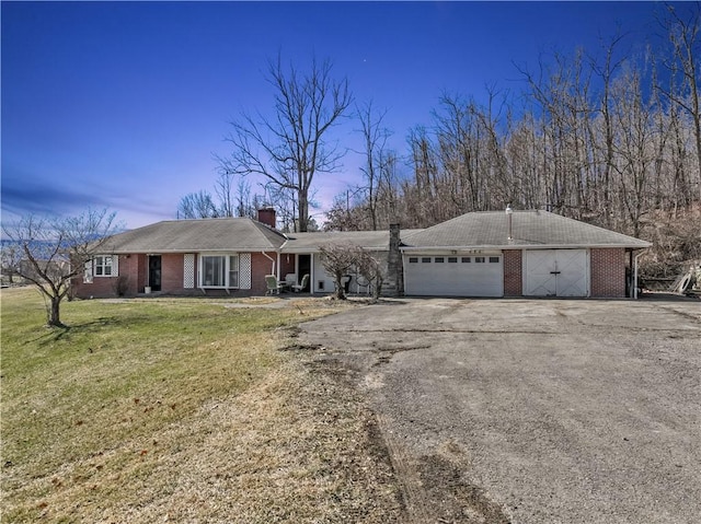 single story home with aphalt driveway, an attached garage, a front lawn, and brick siding