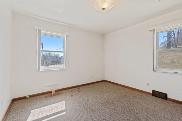 empty room featuring carpet flooring, baseboards, and visible vents