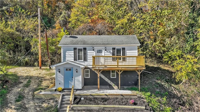 view of front of home featuring an outdoor structure, a deck, and a shingled roof