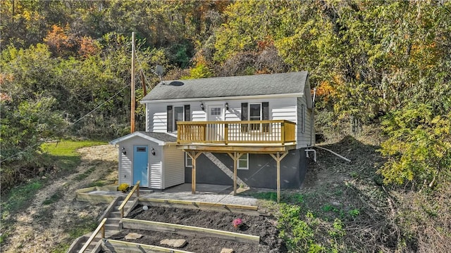 view of front of house featuring a shingled roof, a deck, and a garden