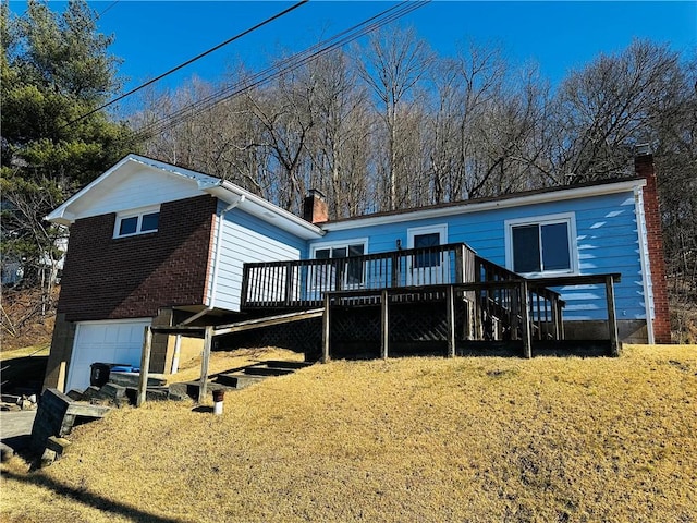 back of house featuring brick siding, stairway, a wooden deck, a chimney, and a garage