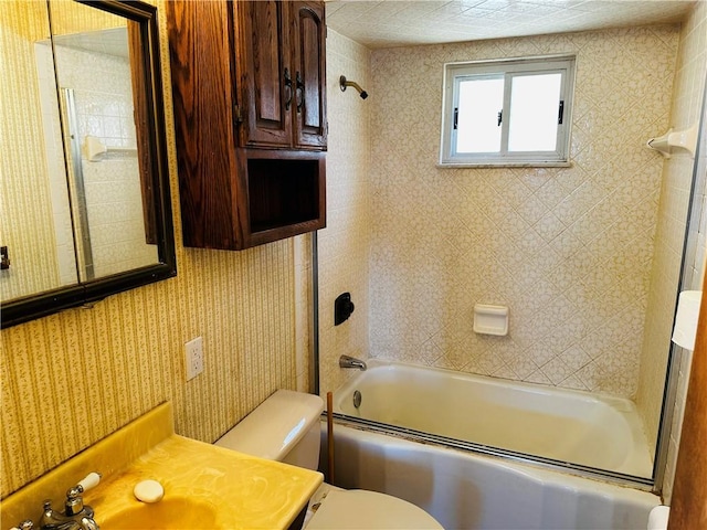 full bathroom with combined bath / shower with glass door, toilet, vanity, and wallpapered walls