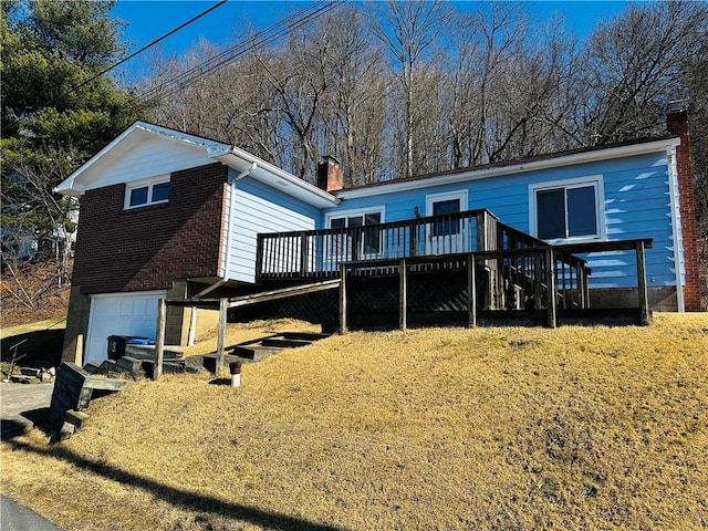 rear view of house featuring a wooden deck, an attached garage, a chimney, and brick siding