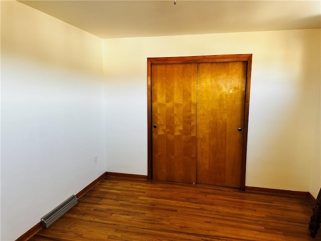 unfurnished bedroom with visible vents, baseboards, a closet, and wood finished floors