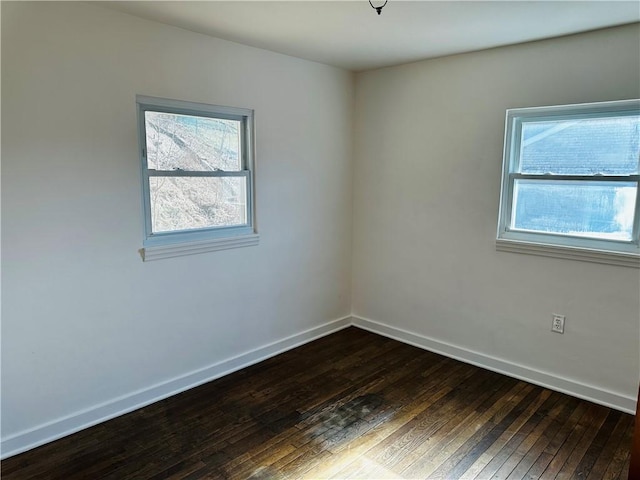 spare room with baseboards and dark wood-type flooring