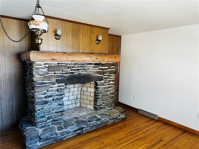 room details featuring a stone fireplace, wood finished floors, visible vents, and baseboards