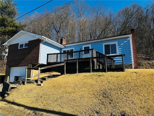 back of property with brick siding, a deck, a chimney, and a garage