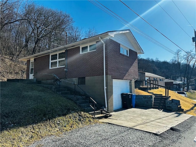 view of property exterior featuring a garage, brick siding, and driveway