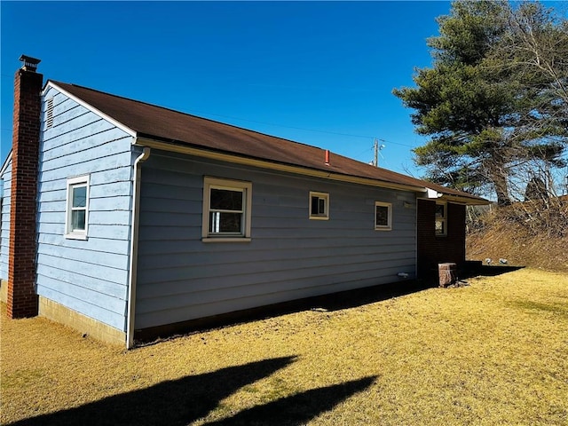 view of side of property with a yard and a chimney