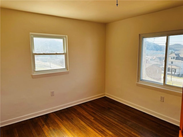 empty room featuring dark wood-style floors and baseboards