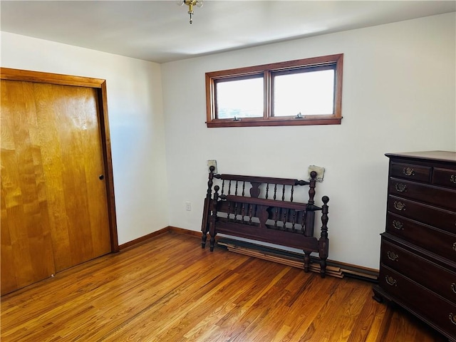 bedroom with a closet, light wood-type flooring, and baseboards