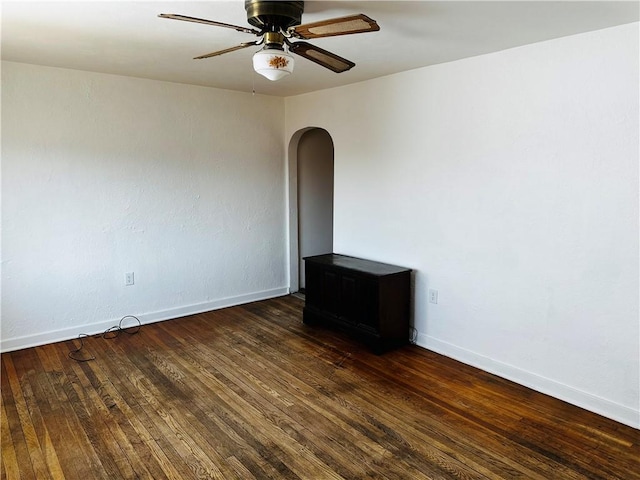 empty room featuring arched walkways, ceiling fan, baseboards, and hardwood / wood-style floors