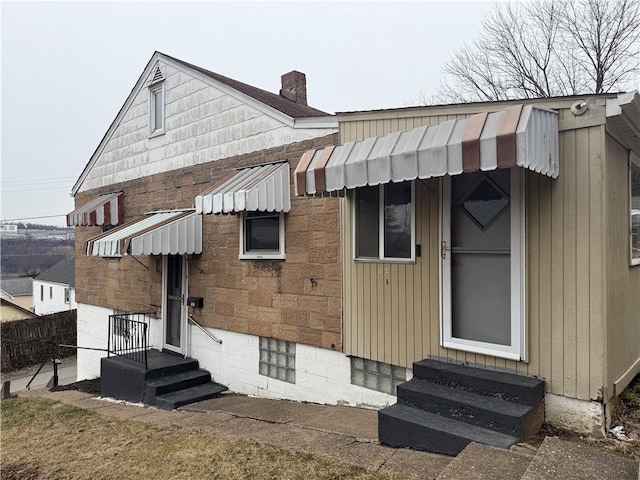 rear view of property featuring a chimney and entry steps