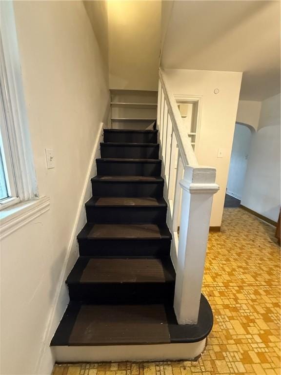 staircase with brick floor and baseboards