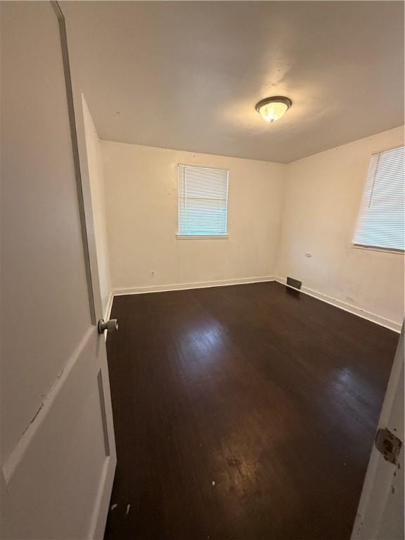 empty room with visible vents, baseboards, and dark wood-style flooring