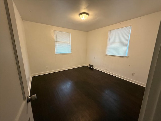 spare room featuring baseboards and dark wood-style flooring