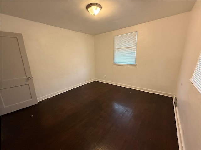 empty room featuring dark wood-style floors and baseboards