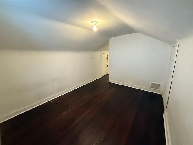 bonus room with vaulted ceiling, baseboards, visible vents, and dark wood-type flooring