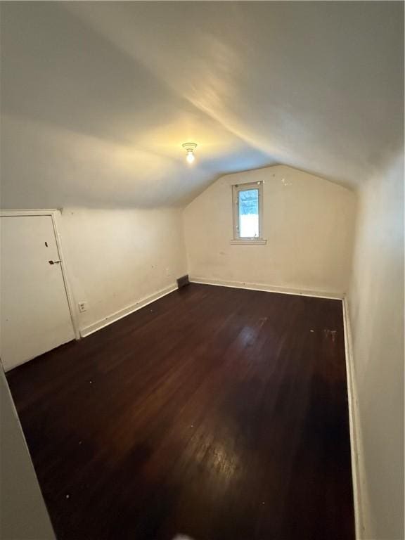 additional living space with dark wood-type flooring, baseboards, and vaulted ceiling