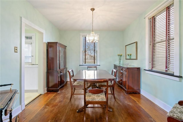 dining space with baseboards, wood-type flooring, and a chandelier