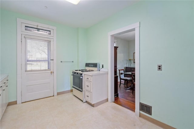 kitchen featuring visible vents, white gas stove, white cabinets, and light countertops