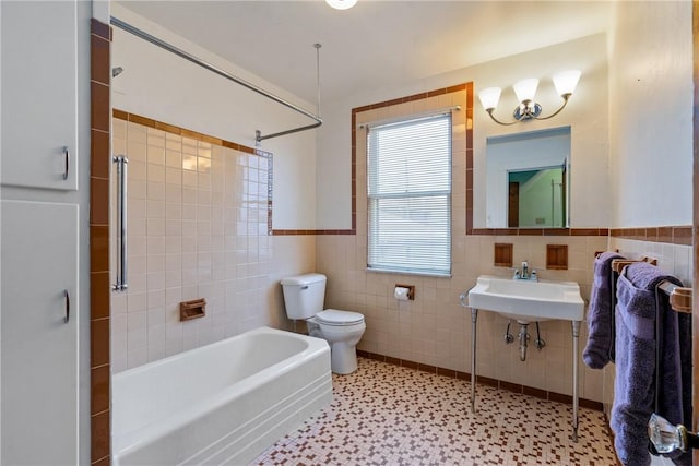 full bath with tile walls, toilet, and wainscoting