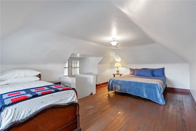 bedroom with baseboards, lofted ceiling, and hardwood / wood-style floors