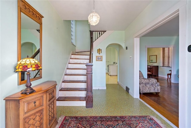 staircase with baseboards, arched walkways, and a chandelier