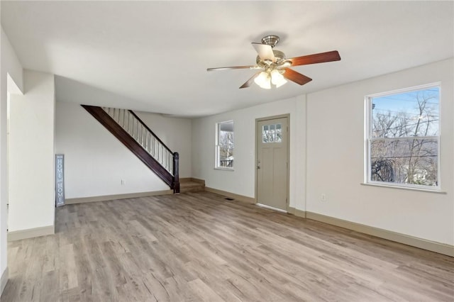 entrance foyer featuring stairway, baseboards, light wood-style floors, and a ceiling fan