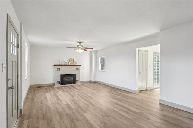 unfurnished living room with a ceiling fan, light wood-style floors, baseboards, and a fireplace