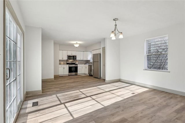 kitchen featuring light wood finished floors, appliances with stainless steel finishes, white cabinets, light countertops, and baseboards