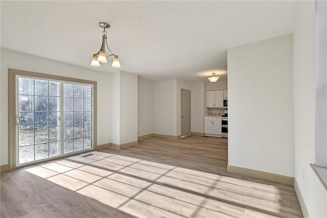 unfurnished room featuring an inviting chandelier, baseboards, and light wood-type flooring