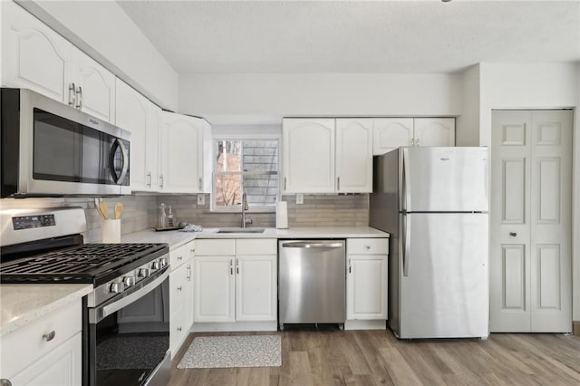 kitchen featuring a sink, appliances with stainless steel finishes, white cabinets, and light wood finished floors