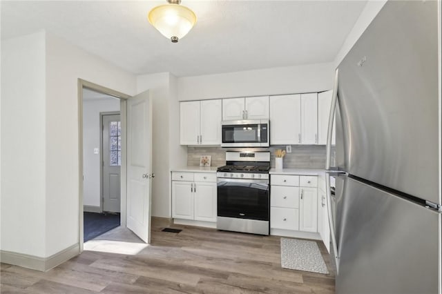 kitchen featuring tasteful backsplash, light wood finished floors, light countertops, stainless steel appliances, and white cabinetry