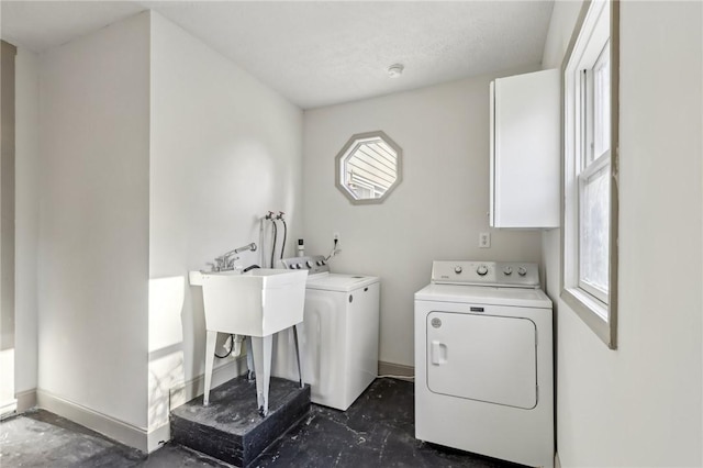 clothes washing area featuring baseboards, independent washer and dryer, and a sink