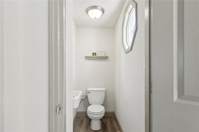 bathroom featuring toilet, baseboards, and wood finished floors