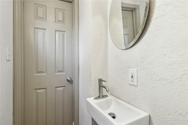 bathroom featuring a sink and a textured wall