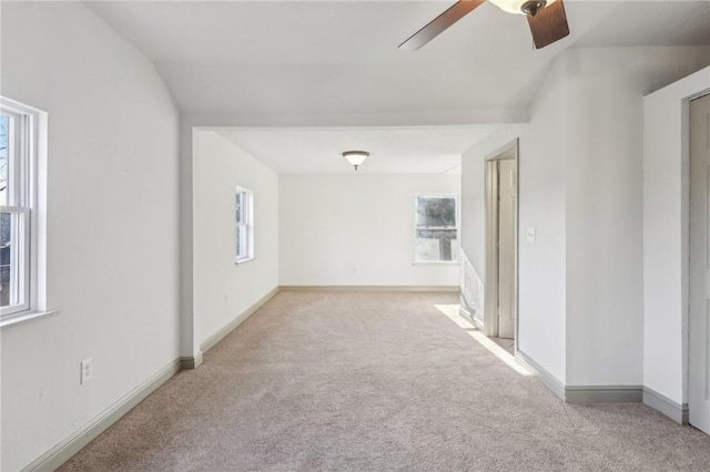 empty room with baseboards, light colored carpet, and ceiling fan