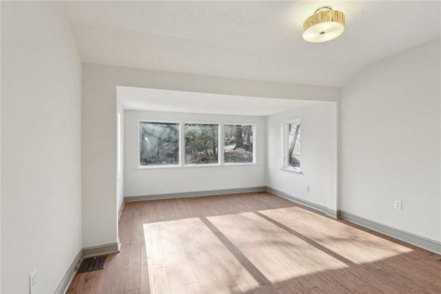 spare room with baseboards and wood finished floors