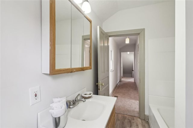 bathroom with a washtub, vanity, and vaulted ceiling