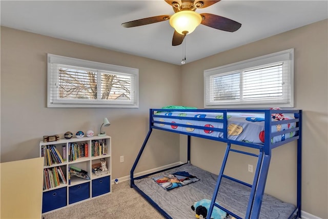 carpeted bedroom featuring multiple windows, baseboards, and ceiling fan