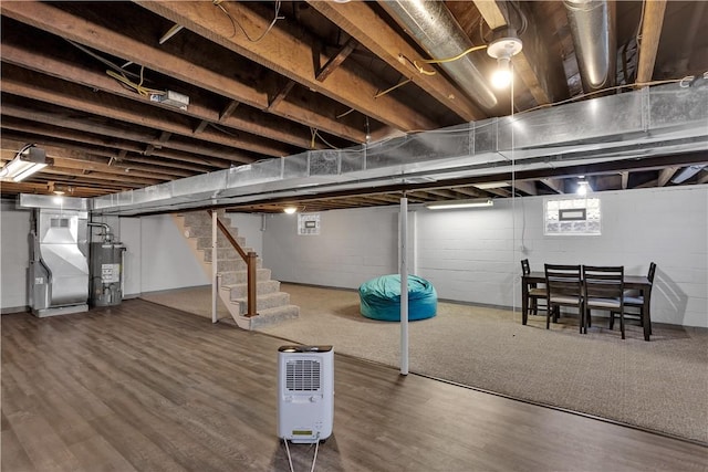 finished basement featuring stairs, heating unit, wood finished floors, and water heater