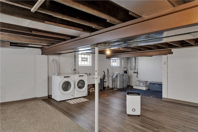 below grade area with wood finished floors, electric panel, washing machine and dryer, and a sink