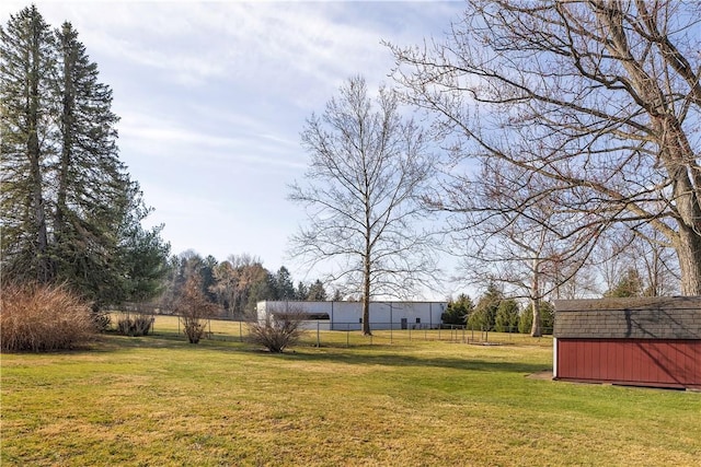 view of yard with an outbuilding, a storage unit, and fence