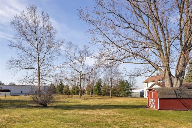 view of yard featuring an outbuilding, a storage unit, and fence