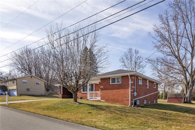 view of side of home with a yard, an outbuilding, and brick siding