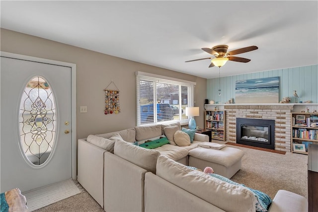 carpeted living area featuring a brick fireplace and a ceiling fan