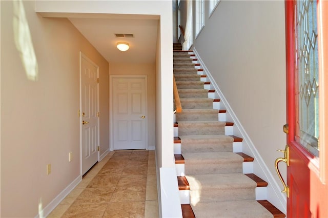 foyer entrance featuring light tile patterned flooring, visible vents, stairs, and baseboards