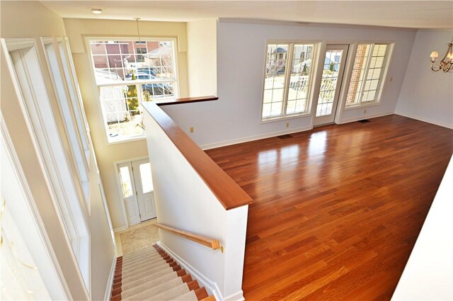 interior space with visible vents, baseboards, an inviting chandelier, and wood finished floors